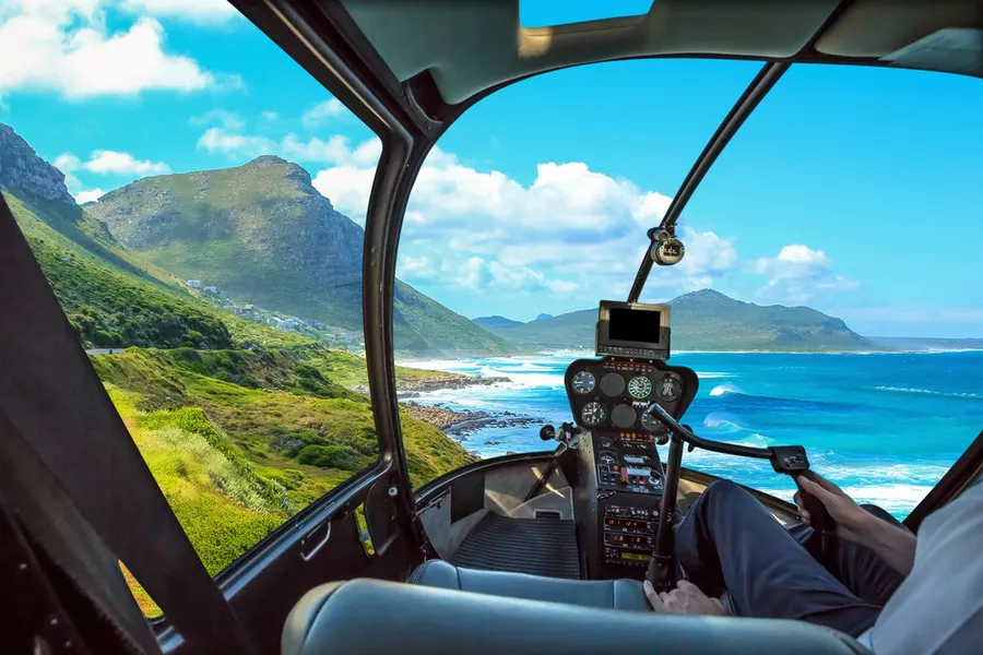 Helicopter cockpit view over Hawaii coastline and mountains
