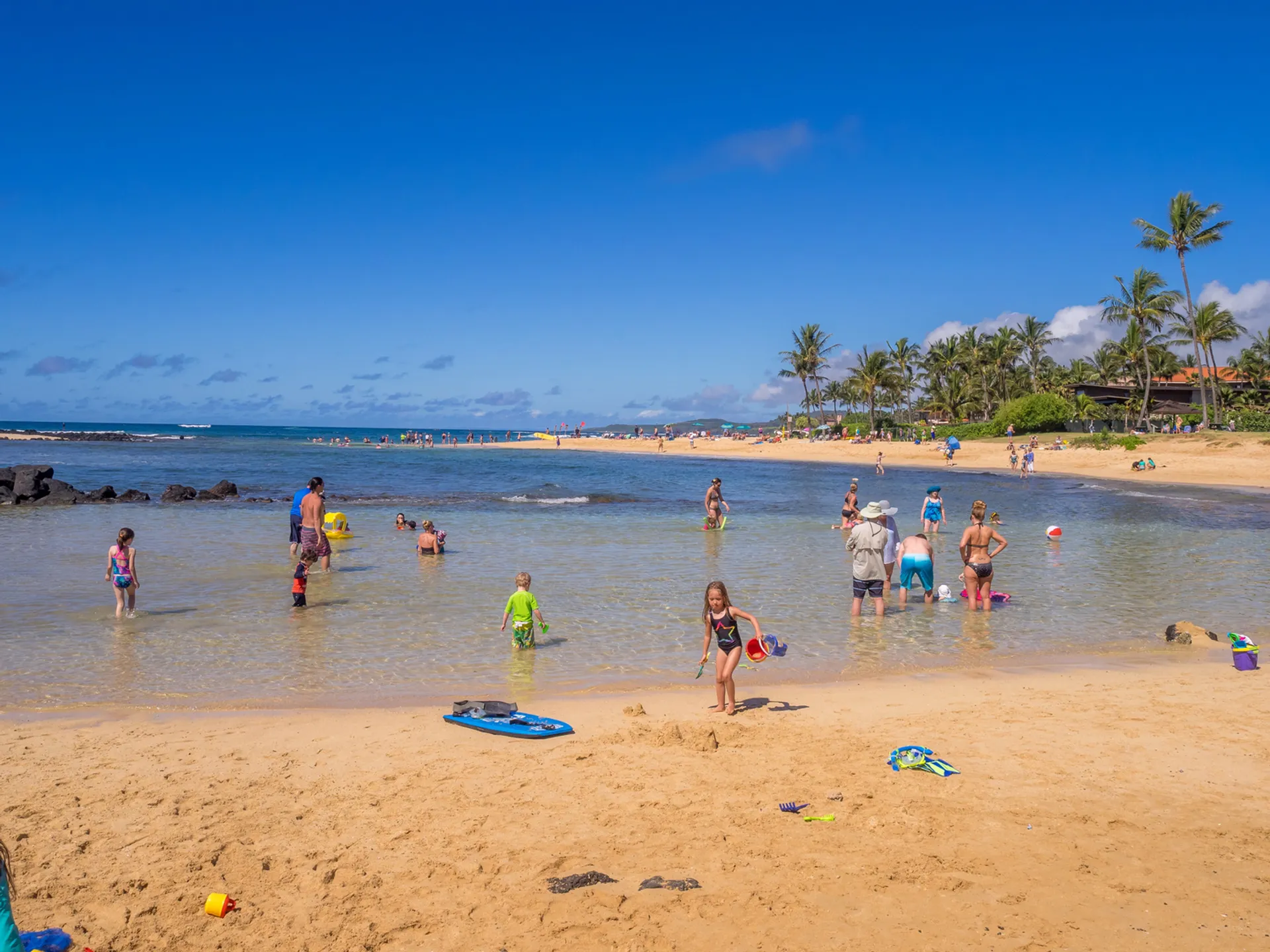 Family enjoying a beautiful day at one of Maui's family-friendly beaches with children playing in clear, calm water
