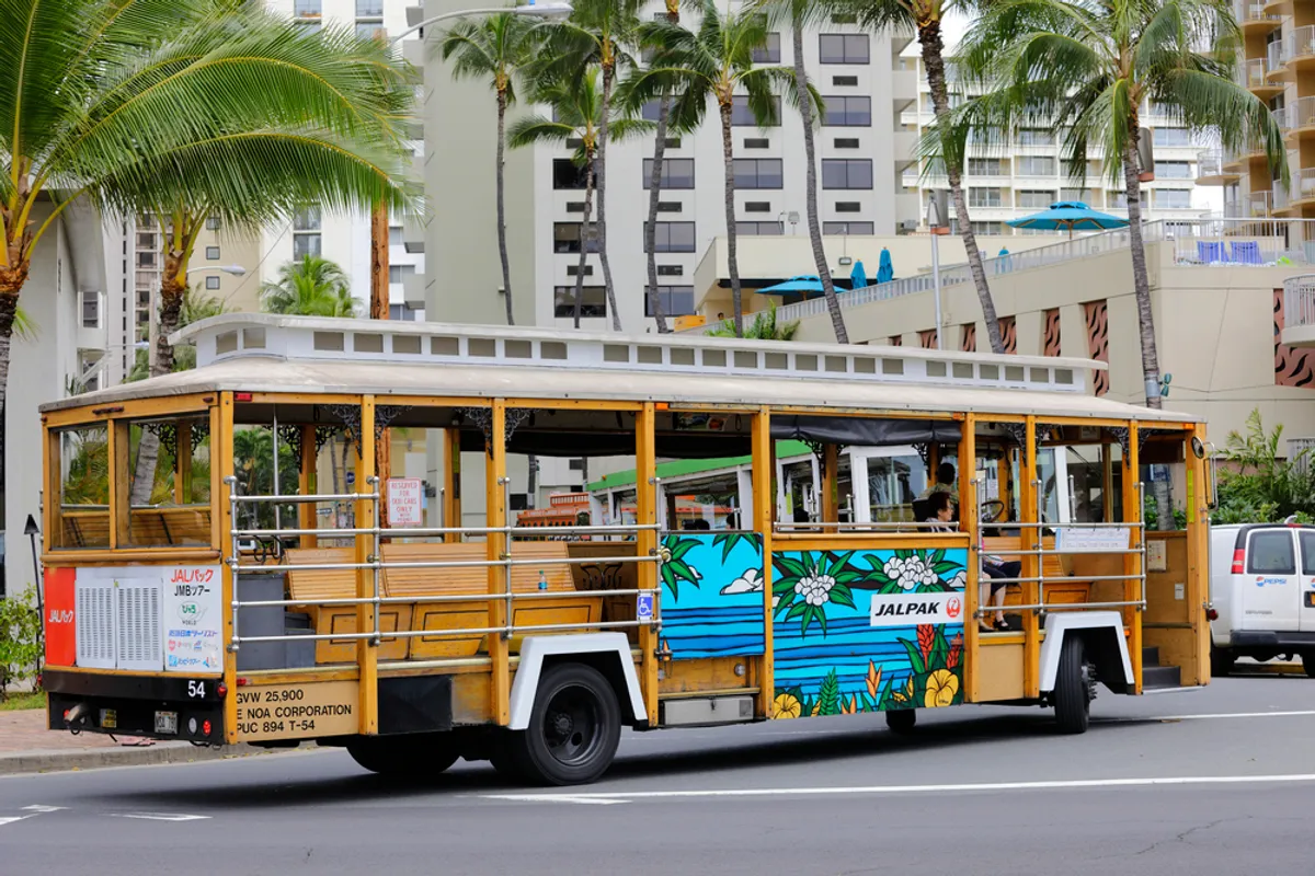 Scenic coastal road on Kauai with rental car driving along the ocean