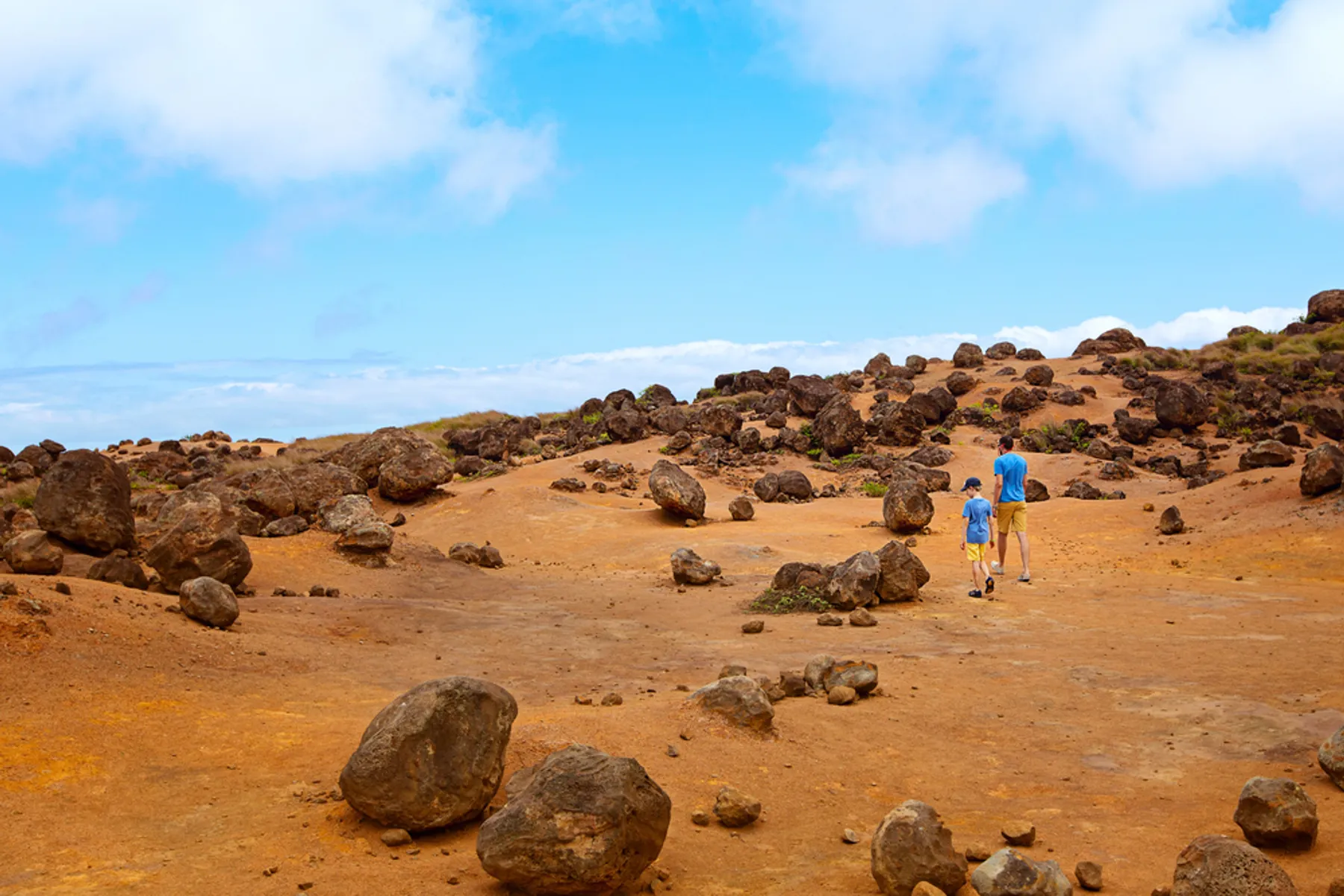 Ancient volcanic boulders scattered across red iron-rich soil at Keahiakawelo