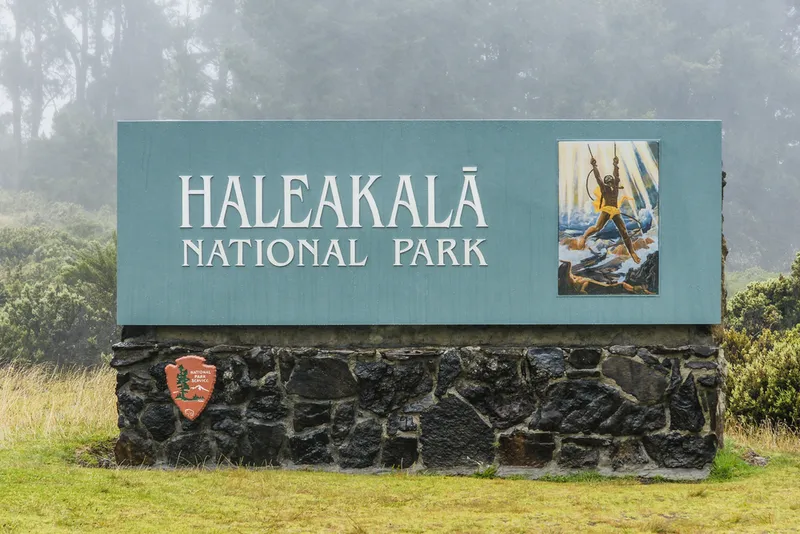 Haleakalā National Park entrance sign with misty mountain landscape