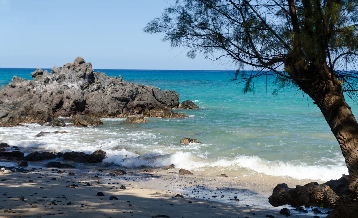 Pristine Waialea Beach showing crystal clear turquoise waters, white sand, and volcanic rock formations