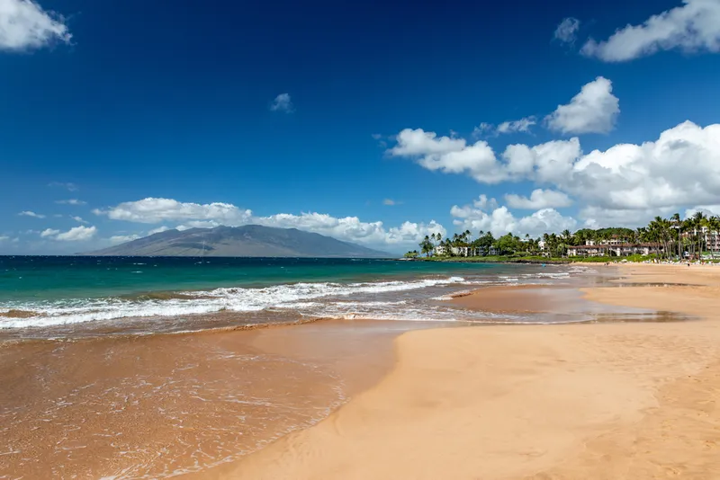 Beautiful Wailea beach with golden sand, turquoise waters, and West Maui Mountains in background