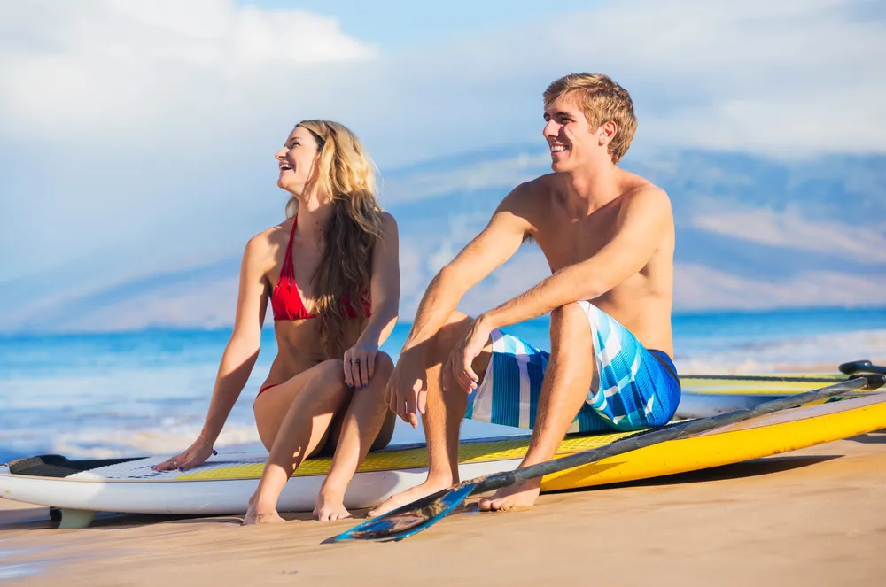 Couple relaxing with paddleboards on Maui beach