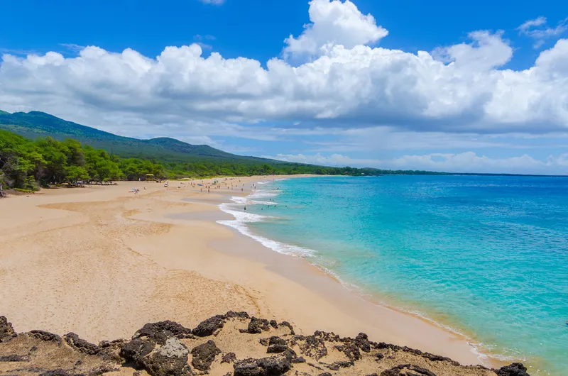 Maui's beautiful red rock coastline meeting the turquoise Pacific Ocean, showing the island's enduring natural beauty and resilience