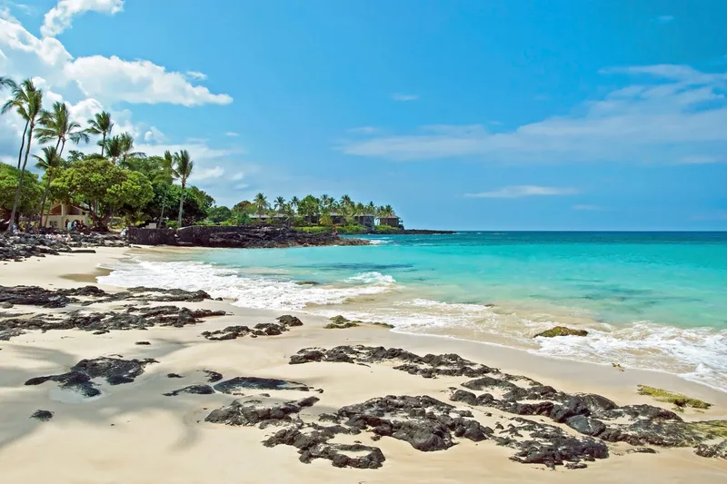 Beautiful white sand beach at Laʻaloa Beach Park with crystal clear turquoise water and palm trees