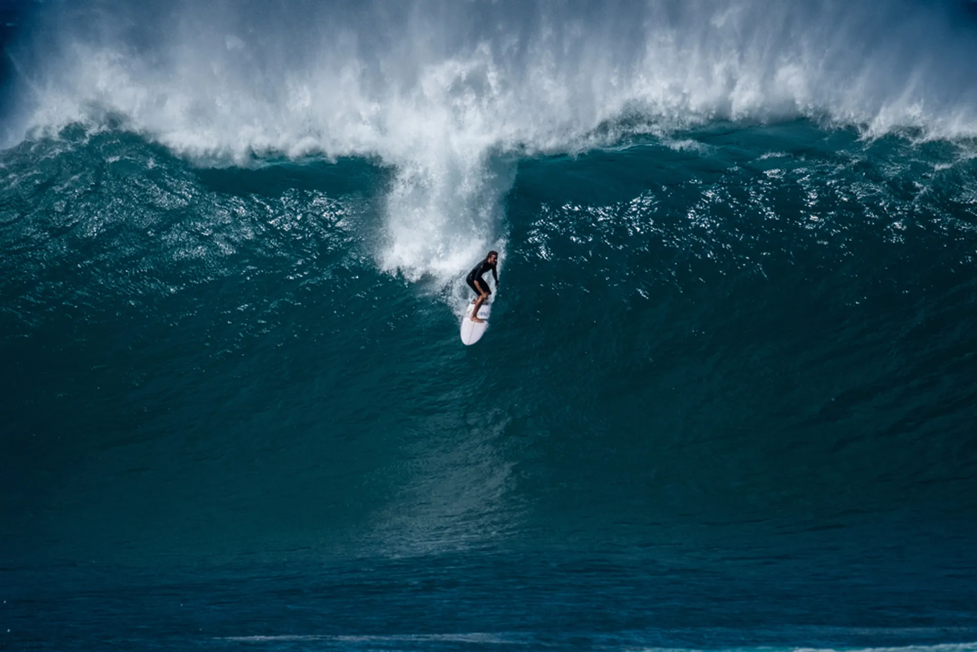 Surfer riding wave at Hanalei Bay with iconic pier visible
