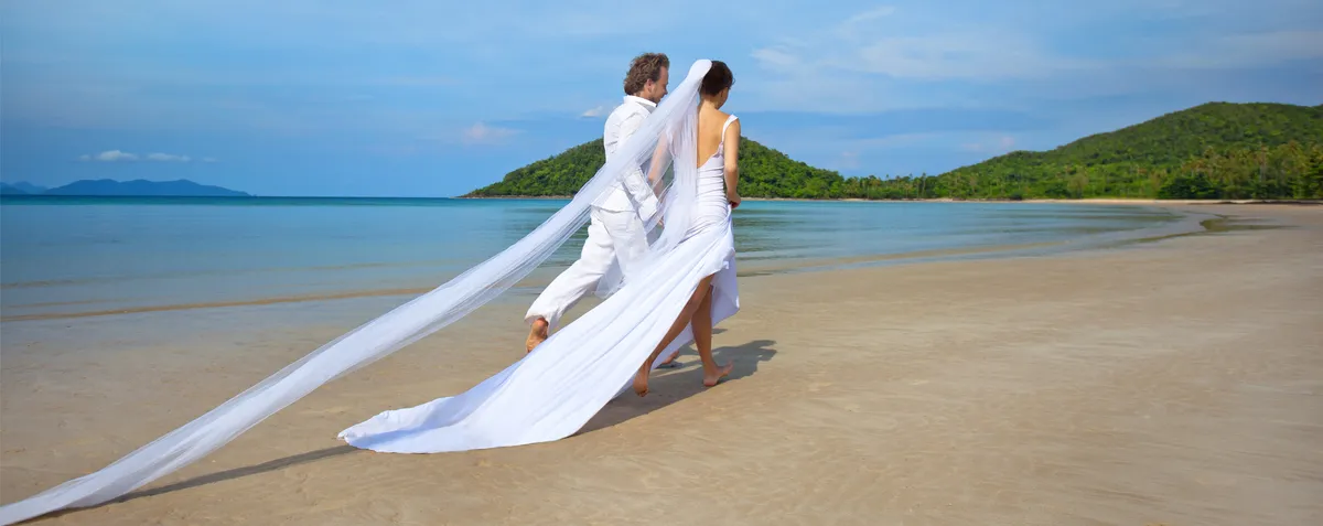 Beautiful Hawaiian beach wedding ceremony with white setup on pristine sand