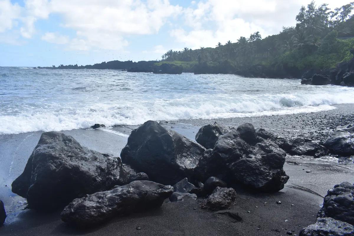 Stunning wide-angle view of Pohoiki's dramatic black sand beach with volcanic rocks and turquoise waters
