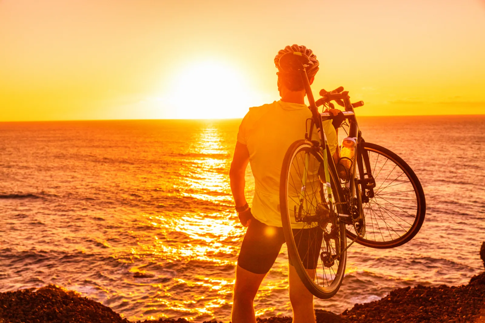 Cyclist with bike on Kauai beach at sunset