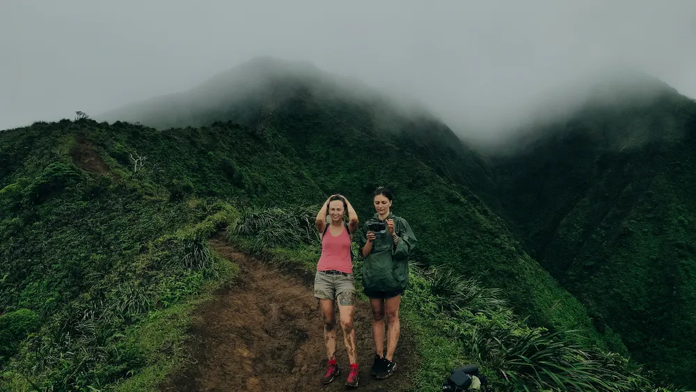 Father and child hiking on a Kauai trail surrounded by lush greenery