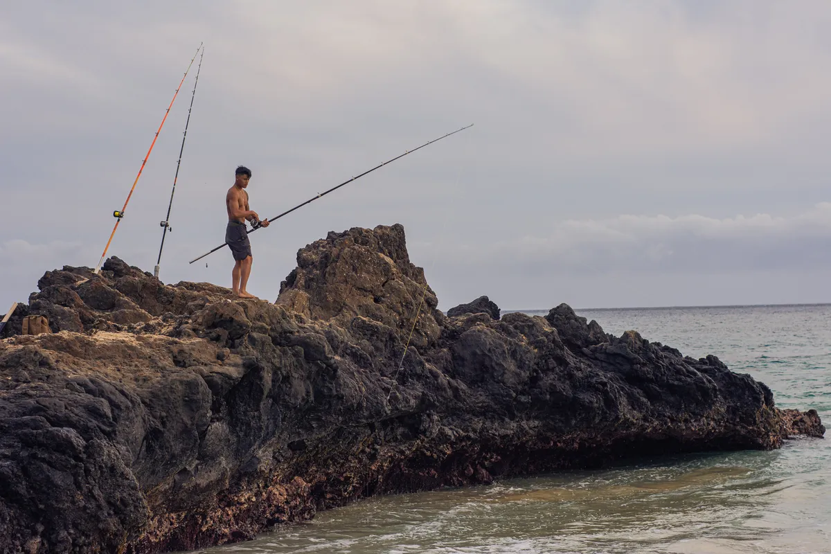 Scenic panoramic view of Kona coast fishing waters with charter boats in the distance and volcanic mountains creating dramatic backdrop