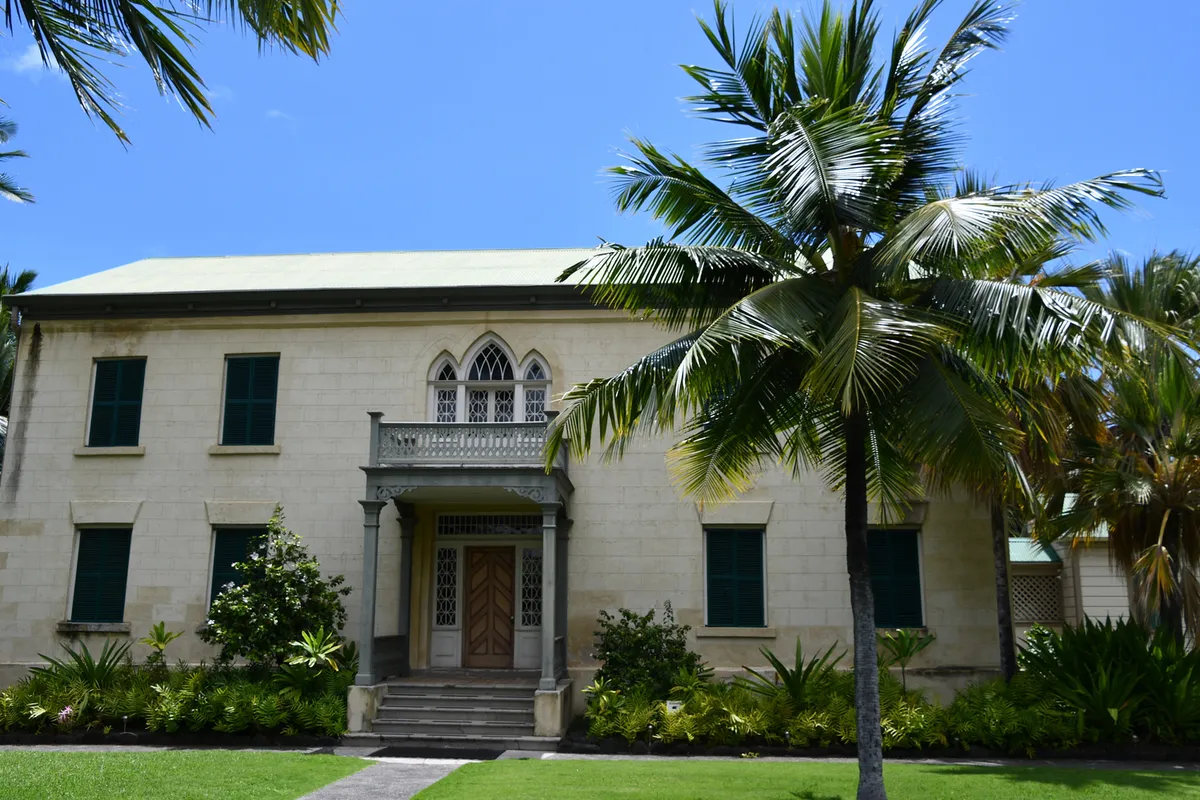 Huliheʻe Palace exterior showing Victorian architecture with green shutters and tropical surroundings