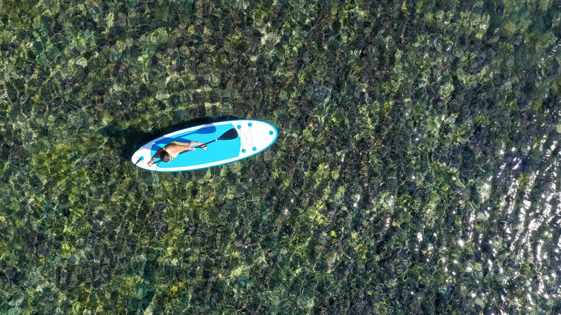 Aerial view of SUP paddler on crystal clear Hawaiian waters