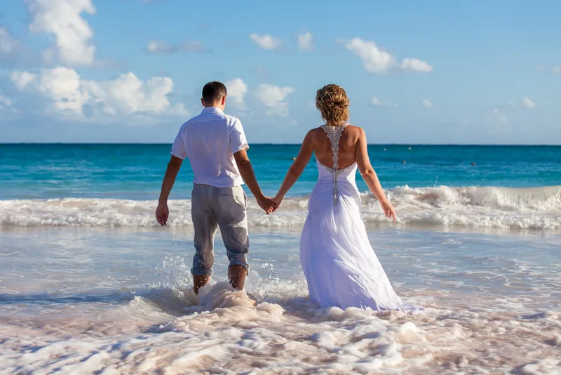 Romantic couple walking hand-in-hand on beautiful Kauai beach at sunset