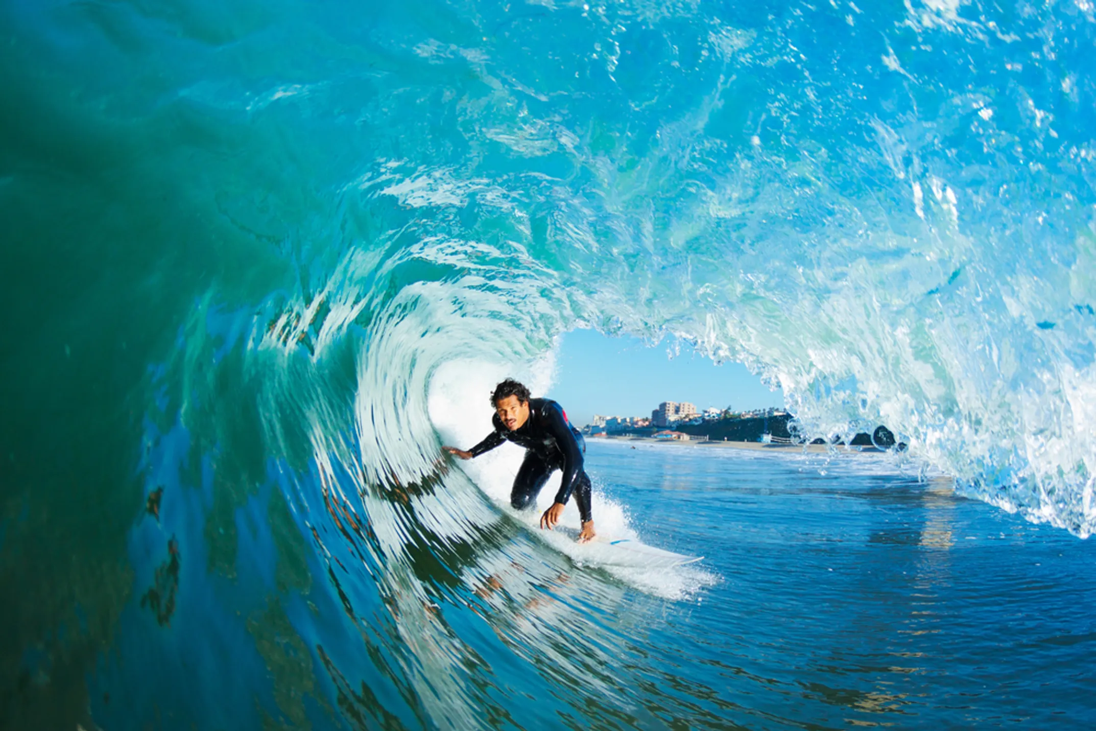 Surfer riding a wave at Hanalei Bay with mountains in background