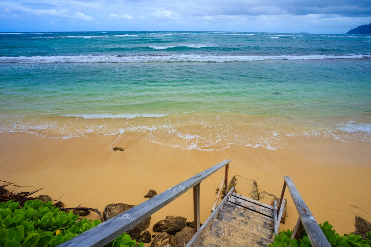 Aerial view of Kauai's North Shore showing the dramatic contrast between calm summer waters and powerful winter waves