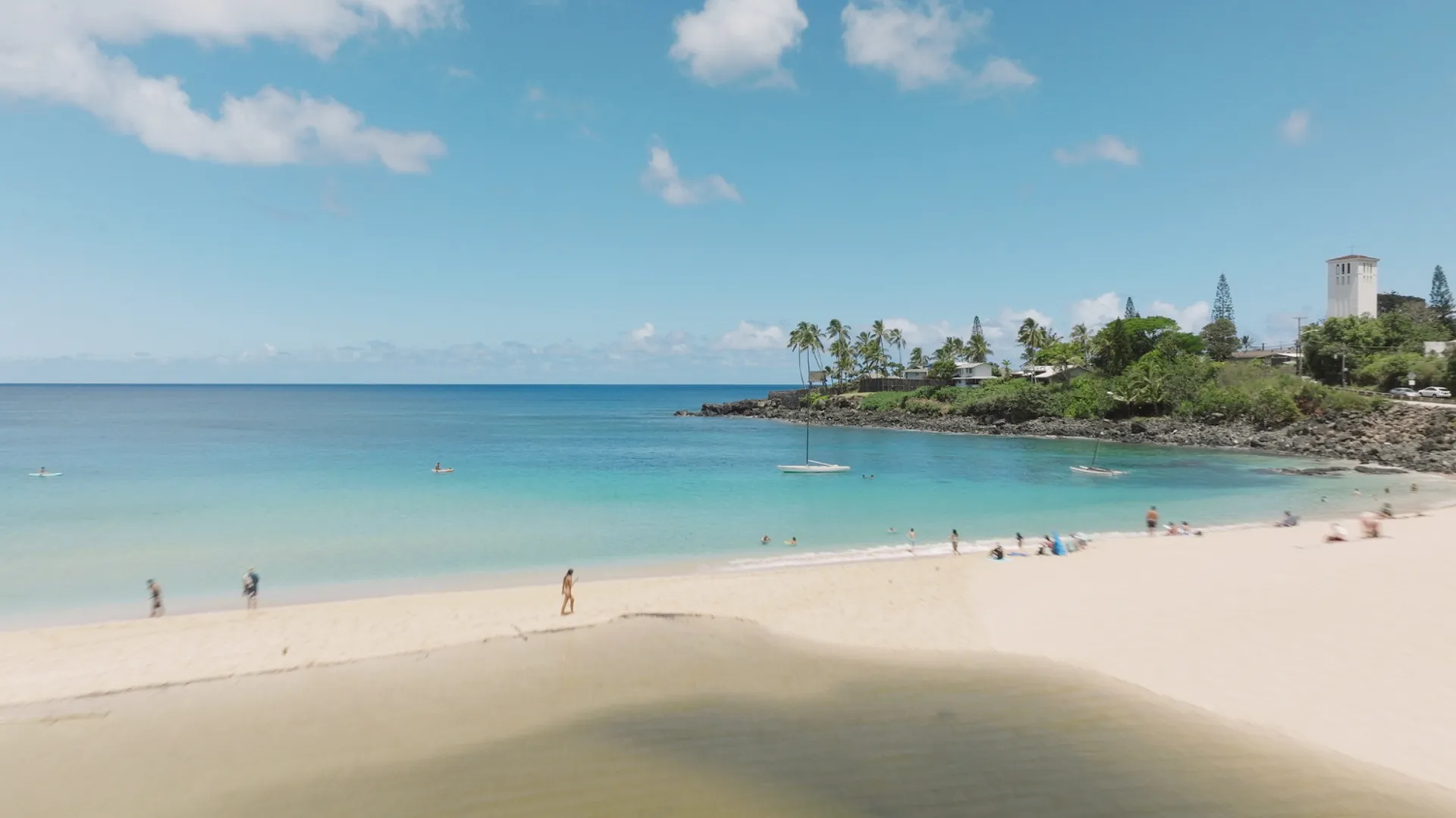 Drone view flying low above Waimea River blue lagoon with white sandy beach