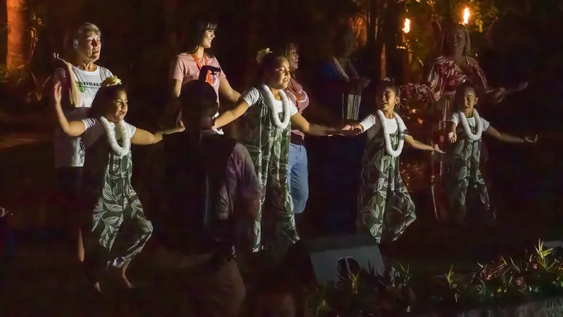 Family participating in traditional Hawaiian cultural activity - lei making, hula, or visiting farmers market with local vendors