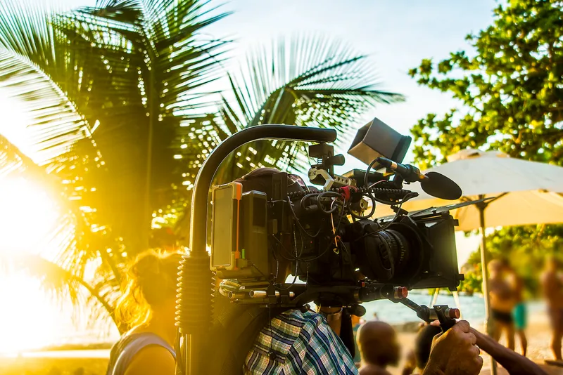 Film camera equipment on tropical Hawaiian beach with palm trees