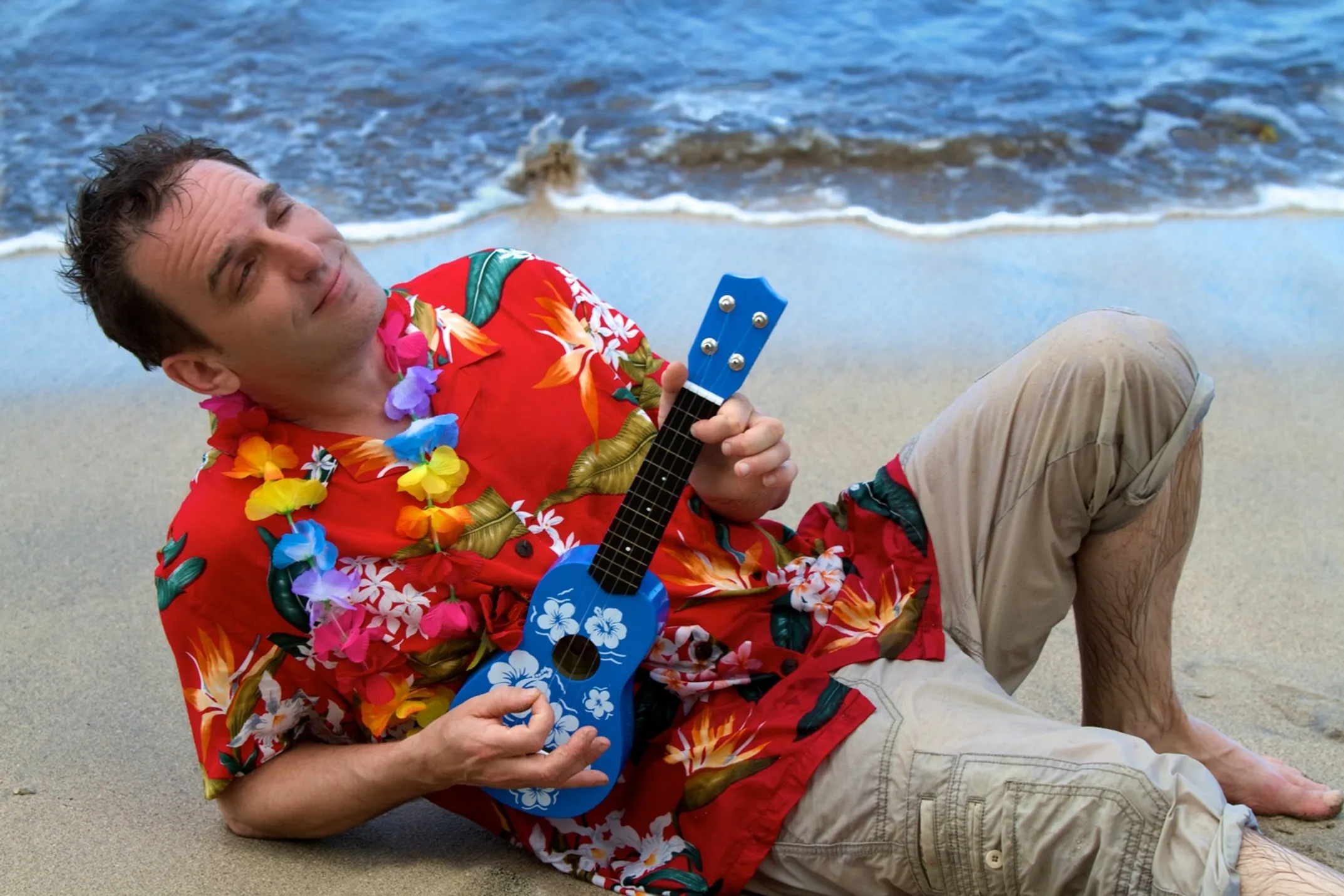 Traditional Hawaiian musician playing ukulele on the beach