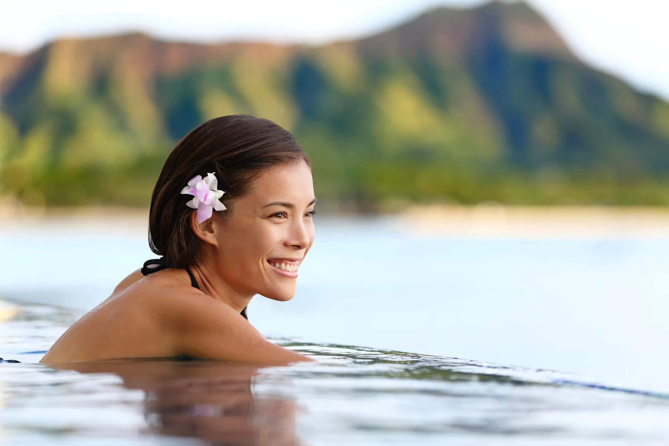 Romantic couple enjoying sunset cocktails at luxury Hawaiian resort with infinity pool overlooking ocean