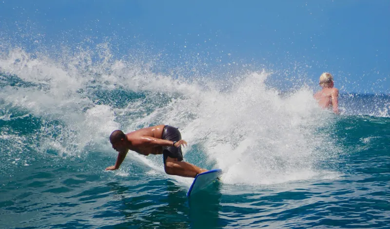 Group surf lesson on Waikiki beach with instructor demonstrating pop-up technique on sand