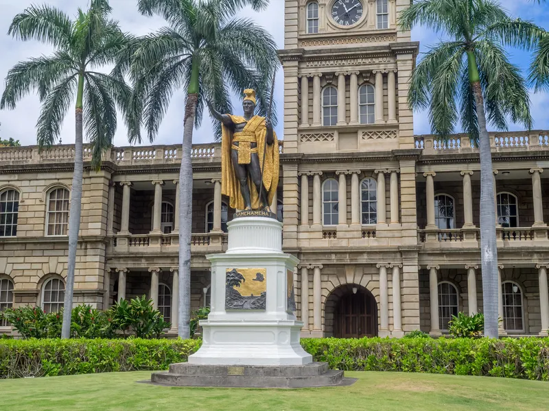 King Kamehameha statue with golden sunset lighting and ceremonial lei