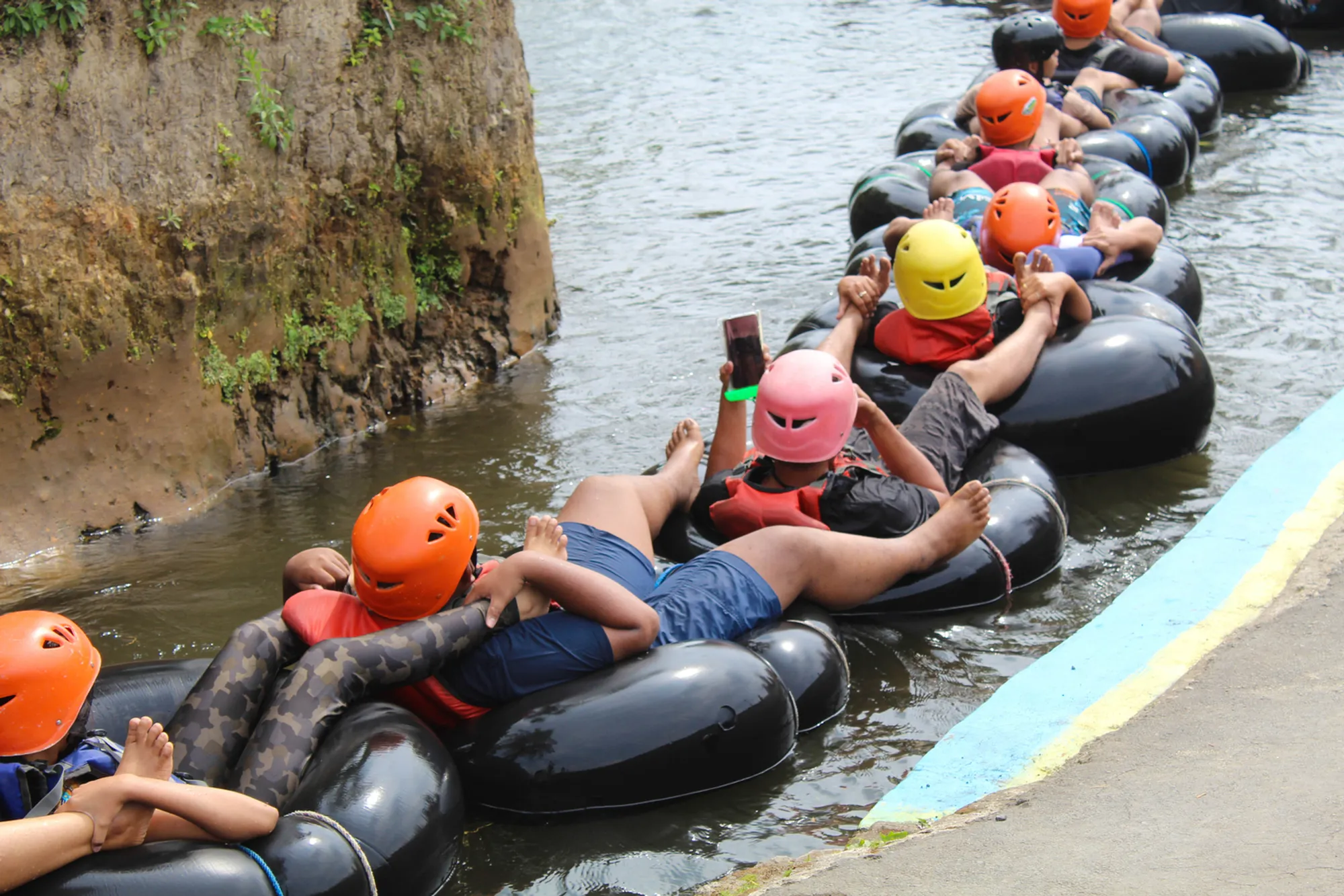 Tubers floating through a lush green irrigation canal on Kauai's historic mountain tubing adventure