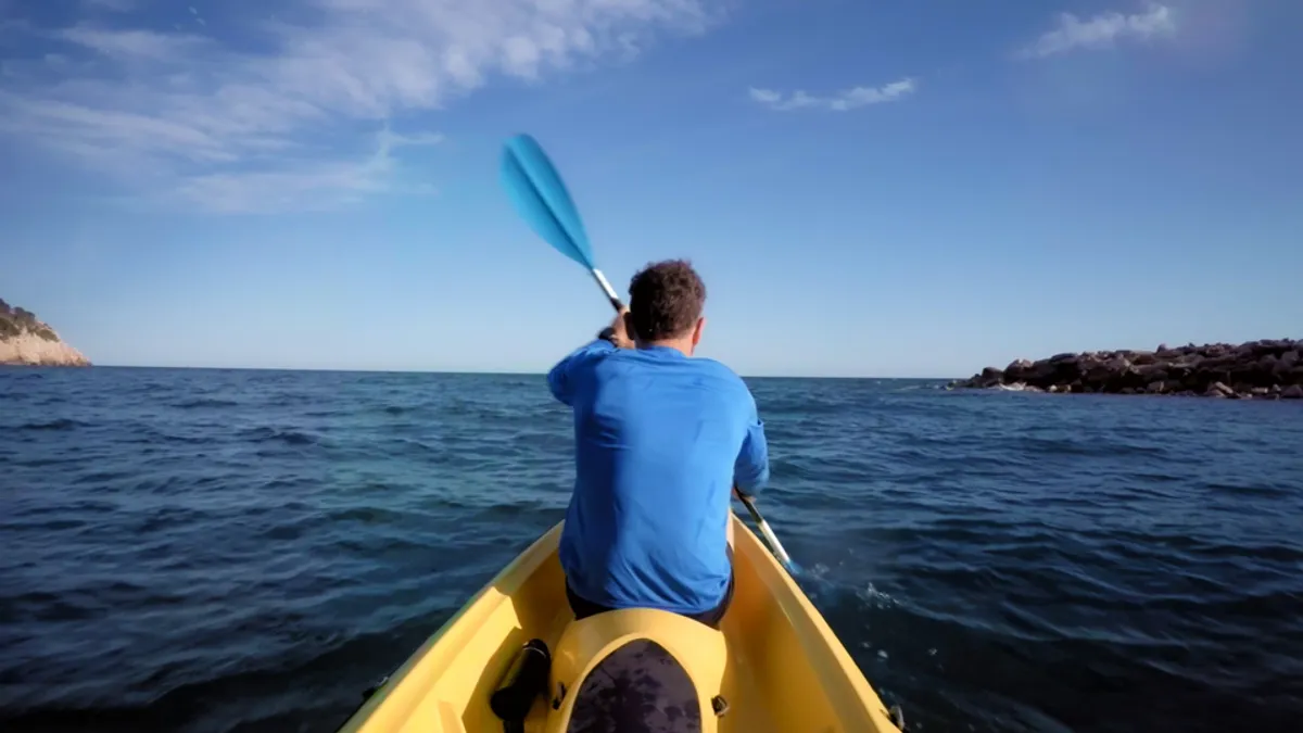 First-person view from kayak paddling through blue choppy waters with adventure partner visible ahead