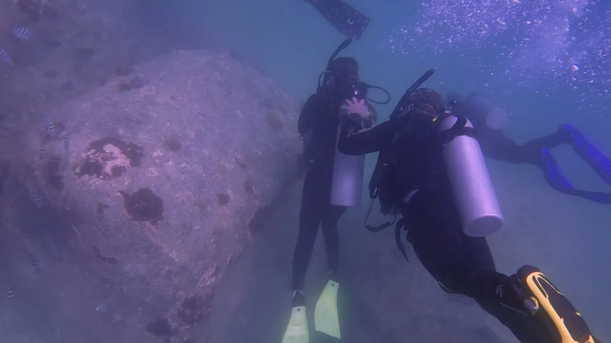 Experienced scuba instructor teaching diving techniques underwater with student diver