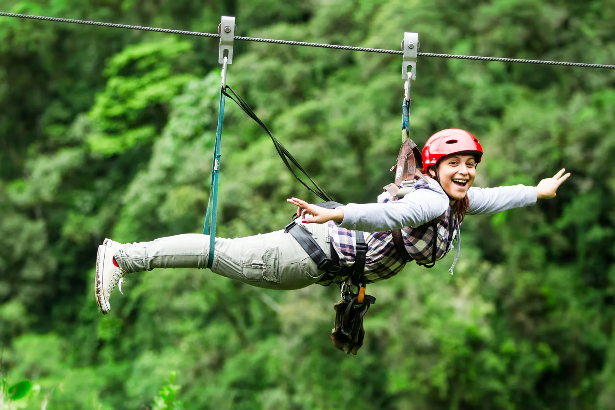 Zipliner soaring through lush Hawaiian rainforest canopy with mountain views