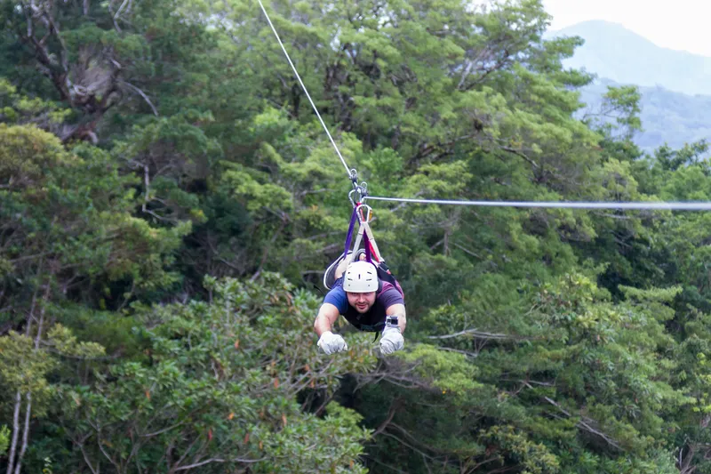 Split image showing zipliners on different islands - Maui rainforest, Big Island waterfalls, Oahu crater landscape